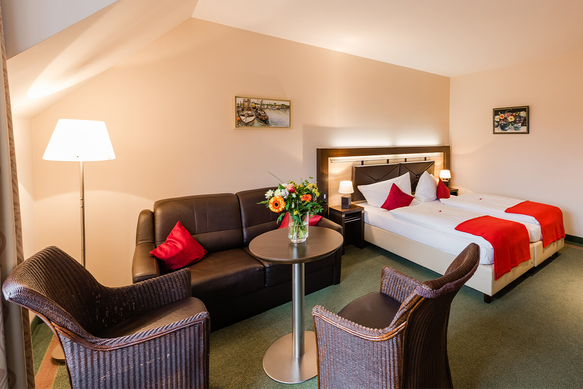 Ein gemütliches Zimmer mit großem Bett und einer bequemen Sitzecke im Hotel am Fischerhafen