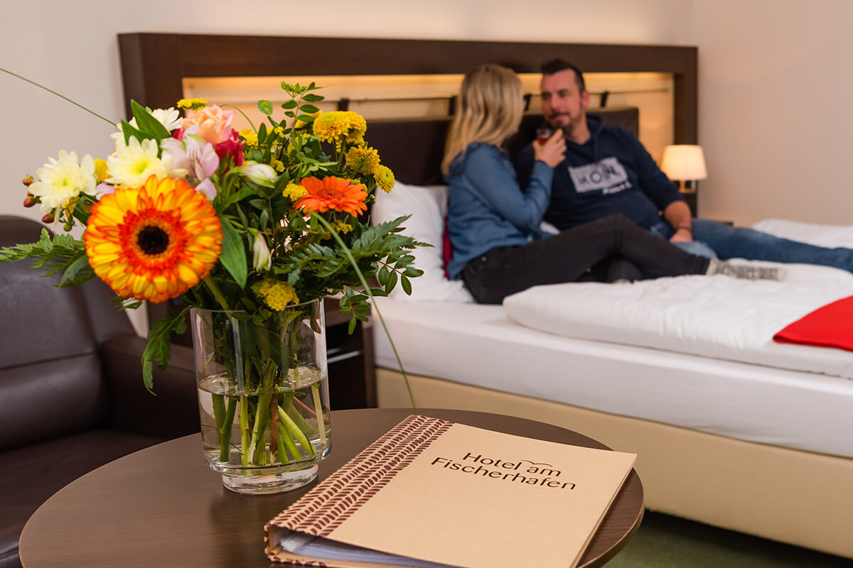 Gemütliches Zimmer mit großem Bett und frischen Blumen im Hotel am Fischerhafen
